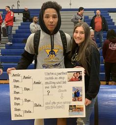 two people standing next to each other holding a sign