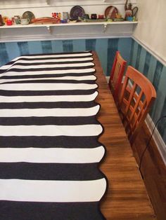 a dining room table with black and white striped rugs on the wooden table top