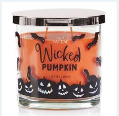 a candle that is inside of a glass jar with pumpkins on the front and sides