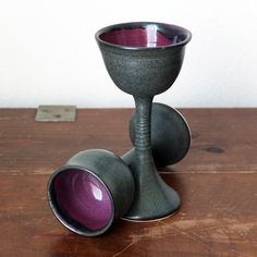 a purple vase sitting on top of a wooden table next to a metal cup holder