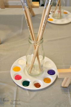 paintbrushes are in a glass jar on a table