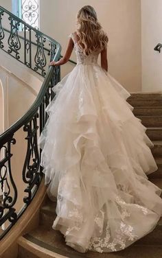 a woman in a wedding dress walking down the stairs with her back to the camera