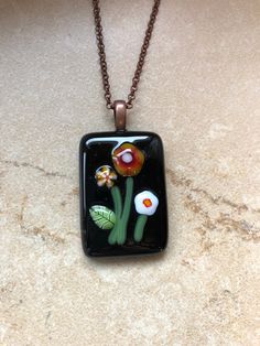 a glass pendant with flowers on it sitting on a counter top next to a chain