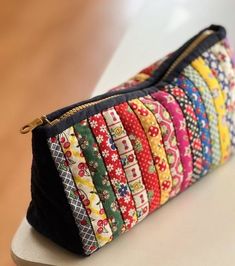 a multi - colored zippered pouch sitting on top of a white counter next to a wooden table