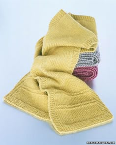 three knitted scarves stacked on top of each other, one yellow and the other red