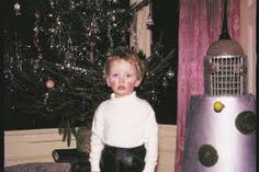 a young boy standing in front of a christmas tree