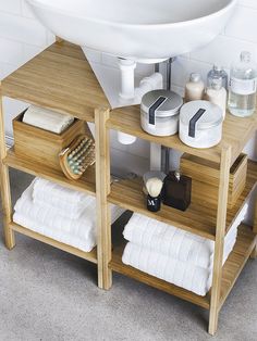 a wooden shelf with towels, soaps and other personal care items on it in front of a sink