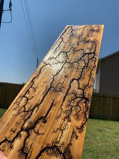 a person holding up a piece of wood that has been stained with black paint and brown streaks