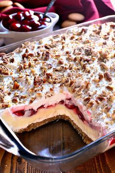 a dessert with cherries and pecans on top in a glass pie dish, ready to be eaten