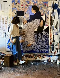 two women are working on a painting in an art studio