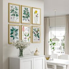 a dining room with white furniture and paintings on the wall