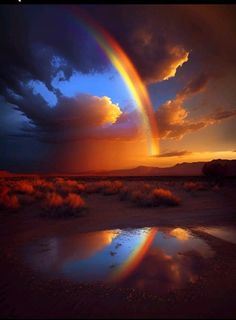 a rainbow appears in the sky over a desert plain at sunset with clouds and water