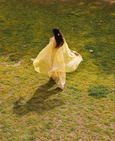 a woman in a yellow dress is walking through the grass