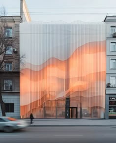 a building with sheered curtains on the side of it's front and cars passing by