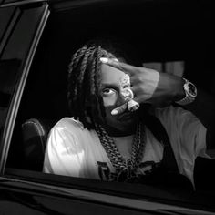 a man with dreadlocks sitting in the back seat of a car holding his hand up to his face