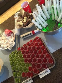 a table topped with cups and trays filled with food next to bowls full of candy