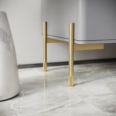 a marble floor with two gold legs and a white cabinet in the corner behind it