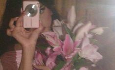 a woman taking a selfie with her camera and flowers in front of her face