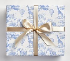 a blue and white gift wrapped in gold ribbon with a giraffe design on it