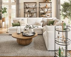 a living room filled with white furniture and lots of greenery on top of it