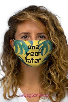 a woman is wearing a face mask with the words one year later painted on it