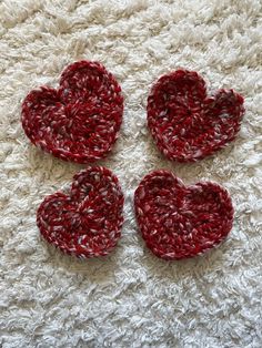 three crocheted hearts sitting on top of a white rug