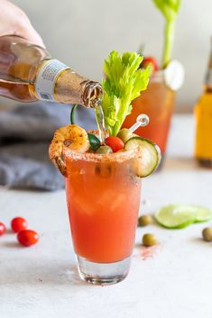 someone is pouring something into a small glass filled with watermelon and garnishes