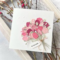 a card with flowers on it sitting next to some branches