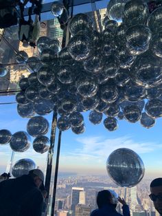 people are looking out from the top of a building with large glass balls hanging from it