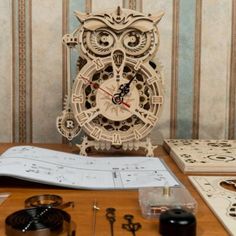 an owl clock sitting on top of a wooden table next to some tools and paper