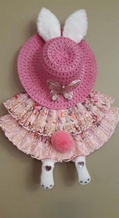 a crocheted pink hat with white pom poms