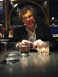 a man sitting at a table with two glasses