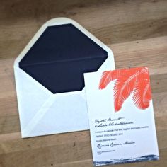 an open envelope with a palm tree on it and a wedding card in the front