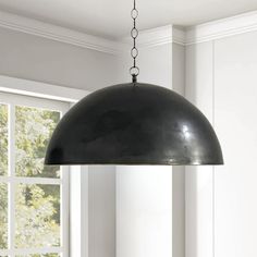 a black lamp hanging from a ceiling in a room with white walls and flooring