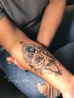 a woman's arm with a rose tattoo on her left forearm and an arrow in the middle