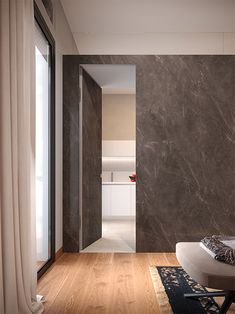 a modern bedroom with marble walls and wood flooring, along with an open door leading to the bathroom