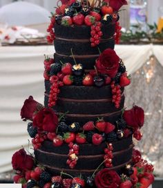 a three tiered chocolate cake with berries and strawberries on top is decorated with flowers