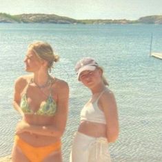 two women in bathing suits standing on the beach