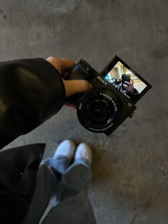 a person holding up a camera to take a photo with their feet on the ground