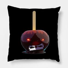 a black pillow with a red apple on it and a wooden stick sticking out of the top