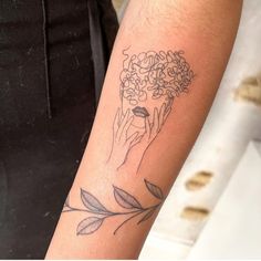 a woman's arm with a tattoo on it that has flowers in her hand