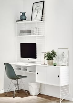 a white desk with a computer on top of it next to a chair and potted plant