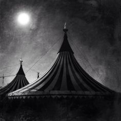 a black and white photo of a circus tent at night with the moon in the sky