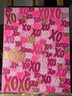 a pink canvas with gold foil on it and the word xo spelled out in small letters