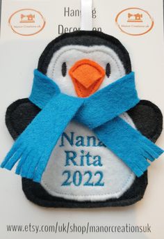 a penguin with a blue scarf and name badge on it's back, in front of a white background