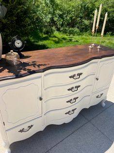 an old dresser is painted white and has black trim on the top with gold accents