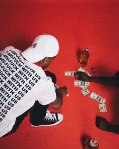 two men sitting on the floor playing with money and liquor bottles next to each other