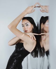 a woman standing in front of a mirror making the shape of a heart