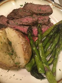 a white plate topped with meat and asparagus