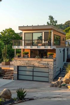 a modern house on the side of a hill with lots of trees and bushes around it